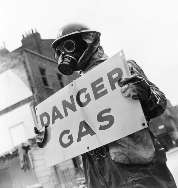 Warden wearing gas mask holding 'Danger, Gas' notice, 8 May 1941.