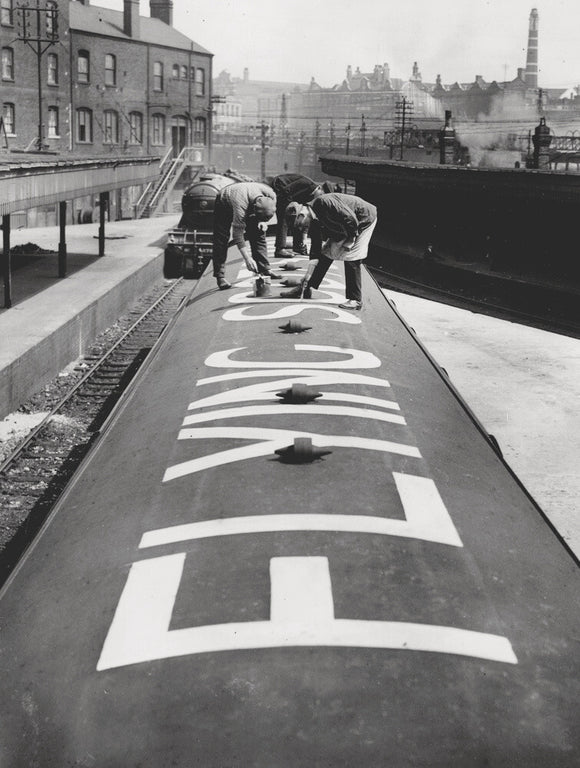The words 'Flying Scotsman' being painted on the roof of one of the train's carriages, 1932.