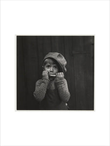 Boy playing the harmonica, about 1925
