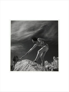 Woman helping child climb onto a rock, about 1935