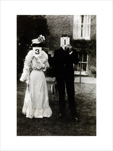 A couple, each holding up a number in front of their face circa 1905