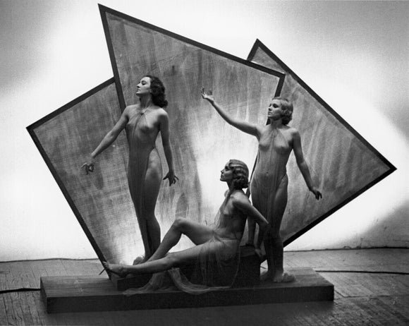 Three near naked women posing on an art deco plinth, c 1920s.
