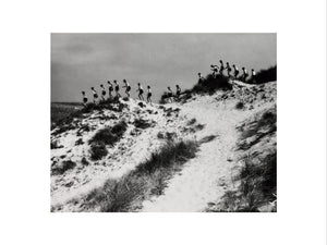 Horizon line of women walking over dunes, about 1930.