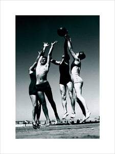 Men and women jumping for a basketball by the sea, 1930s.