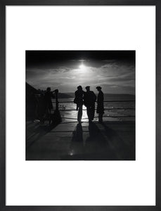 Figures silhouetted by the moon on a promenade, c 1930s.