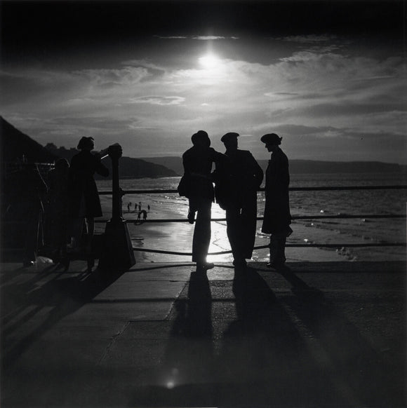 Figures silhouetted by the moon on a promenade, c 1930s.