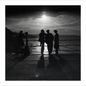 Figures silhouetted by the moon on a promenade, c 1930s.