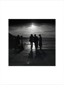 Figures silhouetted by the moon on a promenade, c 1930s.