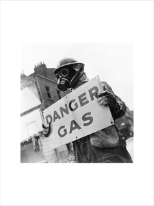 Warden wearing gas mask holding 'Danger, Gas' notice, 8 May 1941.