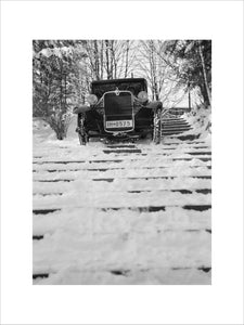 Car driving down snow covered steps. Photographed by Zoltan Glass, c.1930.