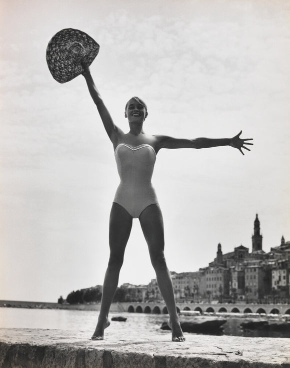 Woman in a swimsuit holding a hat aloft