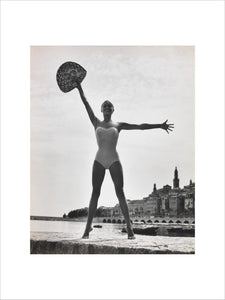 Woman in a swimsuit holding a hat aloft