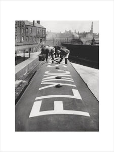 The words 'Flying Scotsman' being painted on the roof of one of the train's carriages, 1932.