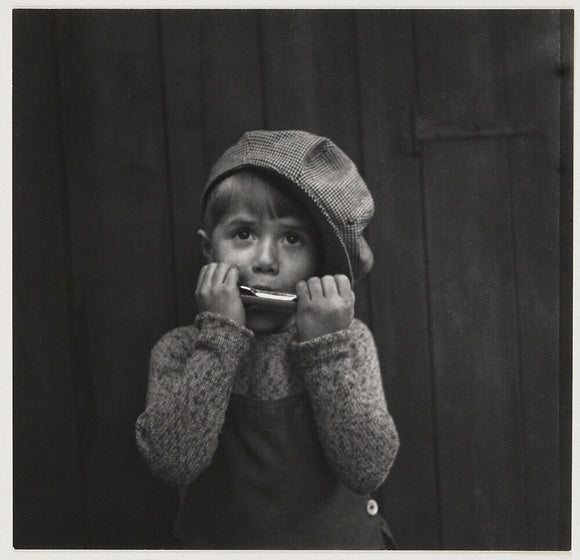 Boy playing the harmonica, about 1925