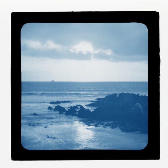 A magic lantern slide showing a seascape with rocks by Birt Acres, c. 1893. (Blue carbon for projection).
