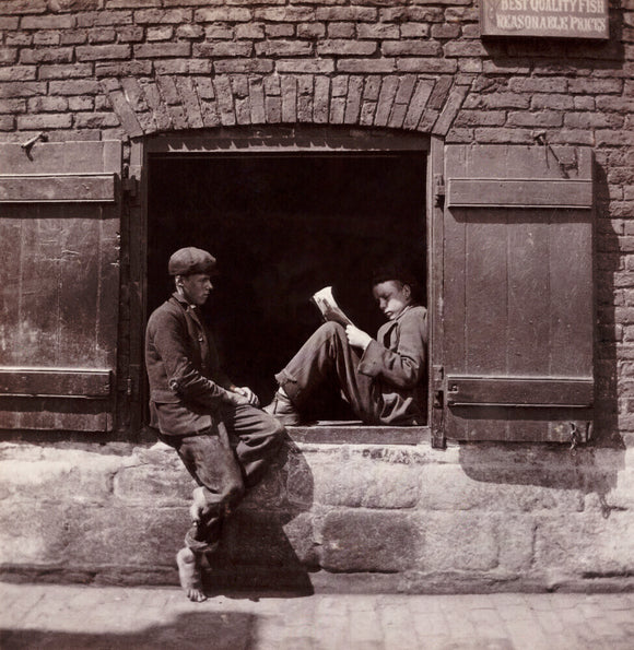 Two boys sitting on a window ledge, c 1905.
