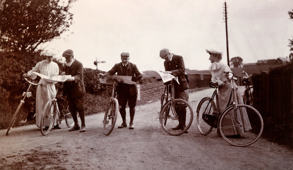 Cyclists looking at maps, c 1900.